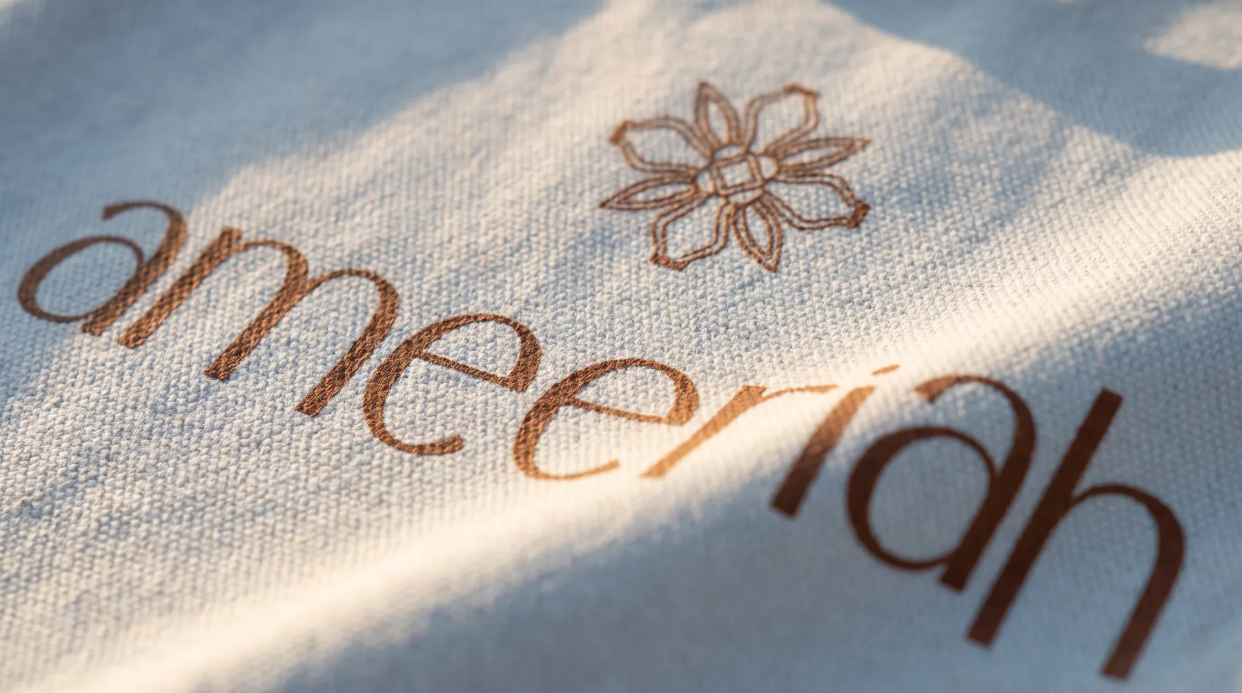 AMEERIAH rosette and wordmark printed on Still Water blue canvas, close up